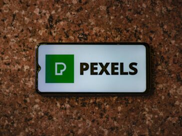 A smartphone displaying the Pexels app logo on a granite tabletop.